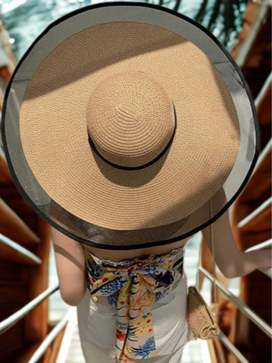 femme de dos qui marche avec un chapeau de paille beige vue du haut